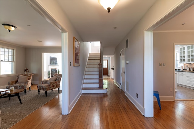 staircase featuring baseboards, crown molding, visible vents, and hardwood / wood-style flooring
