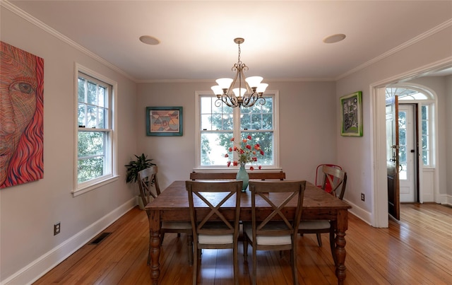 dining space featuring visible vents, baseboards, light wood finished floors, a notable chandelier, and ornamental molding