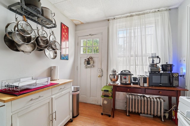 227 Valentine Ln, Yonkers, NY 10705 - kitchen with radiator, black microwave, white cabinets, light wood-style flooring, and butcher block counters