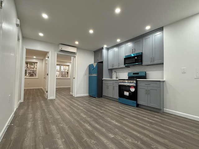 kitchen with electric range, dark wood-style floors, gray cabinets, an AC wall unit, and freestanding refrigerator
