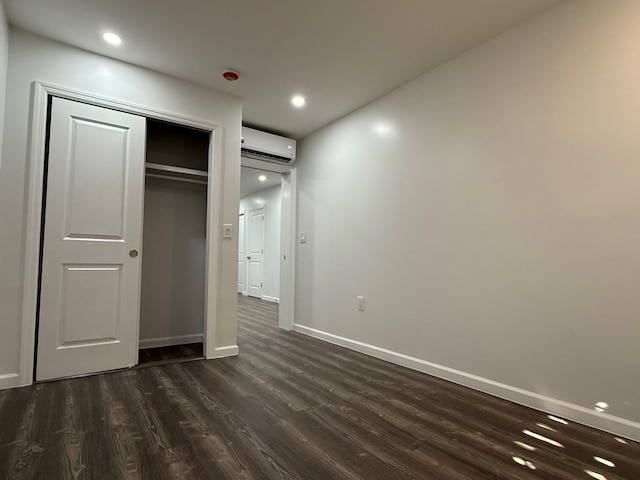 unfurnished bedroom featuring baseboards, a closet, a wall unit AC, and dark wood-style flooring