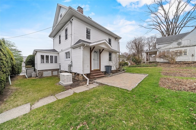 back of property with entry steps, a patio, a lawn, and a chimney