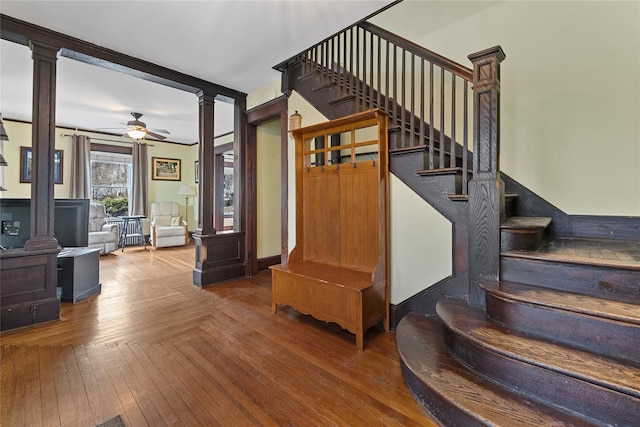 stairs with ornate columns, parquet floors, and a ceiling fan