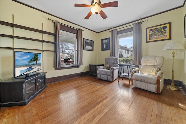 sitting room featuring crown molding, ceiling fan, wood-type flooring, and baseboards