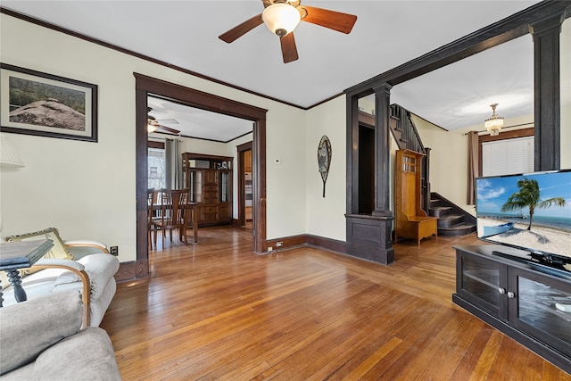 living room featuring light wood-style floors, ornate columns, a ceiling fan, and ornamental molding