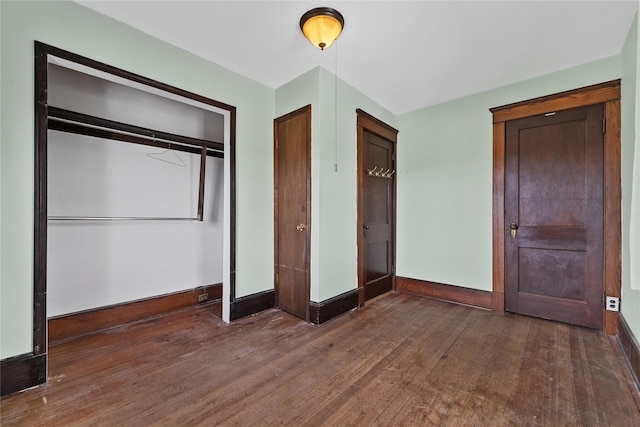 unfurnished bedroom with a closet, baseboards, and hardwood / wood-style floors