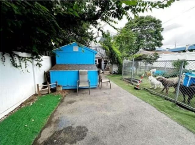 view of patio / terrace with an outbuilding, a fenced backyard, and a shed