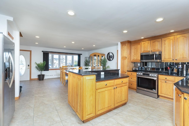 kitchen with recessed lighting, a center island, dark stone counters, appliances with stainless steel finishes, and baseboard heating