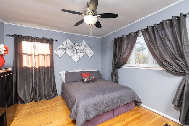 bedroom with baseboards, wood finished floors, ceiling fan, and ornamental molding
