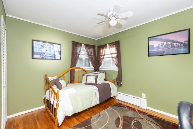 bedroom featuring baseboards, ornamental molding, wood finished floors, and a baseboard radiator