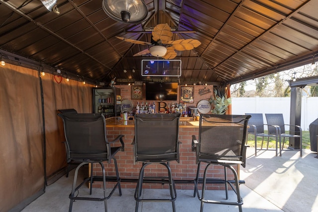 view of patio with outdoor dry bar and fence