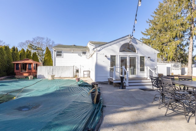 rear view of house with fence, outdoor dining area, a patio area, and a fenced in pool