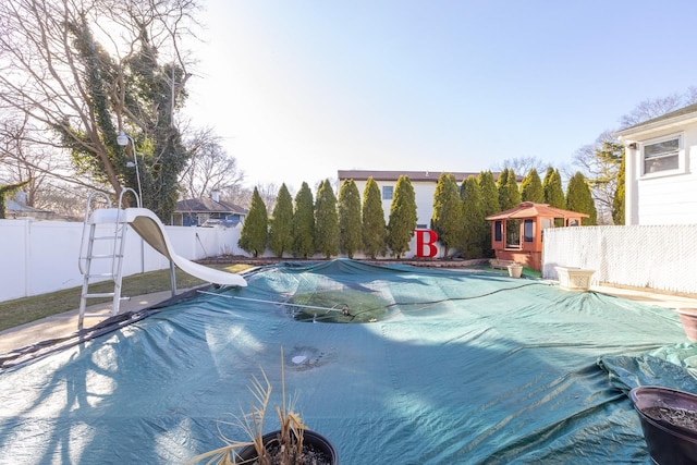 view of pool with a fenced backyard, a water slide, and a fenced in pool