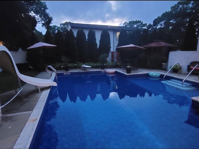 outdoor pool featuring a water slide, a patio area, and a diving board