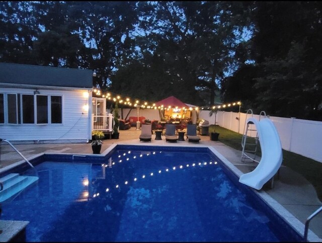 view of pool featuring a fenced backyard, a fenced in pool, a water slide, and a patio