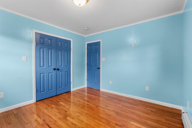 24 Patricia Ln, Washingtonville, NY 10992 - unfurnished bedroom with a closet, crown molding, a baseboard radiator, baseboards, and light wood-style floors
