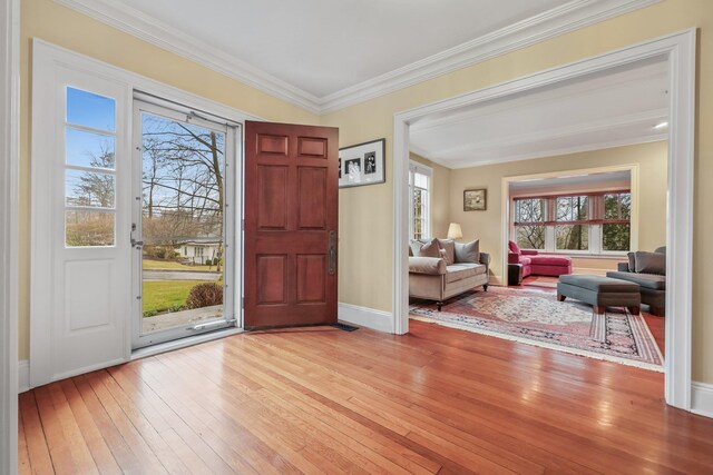 entrance foyer with baseboards, ornamental molding, light wood-style flooring, and a healthy amount of sunlight