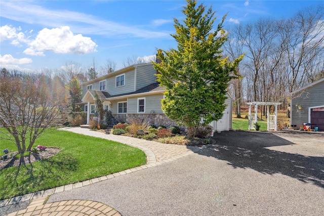 view of front of home with a pergola, stone siding, aphalt driveway, and a front yard