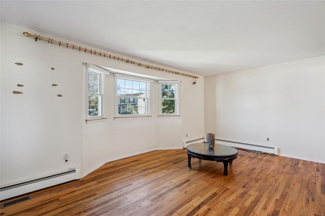 spare room featuring baseboards, baseboard heating, and wood finished floors
