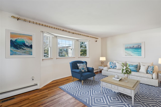 living room featuring a baseboard heating unit, baseboards, and wood finished floors