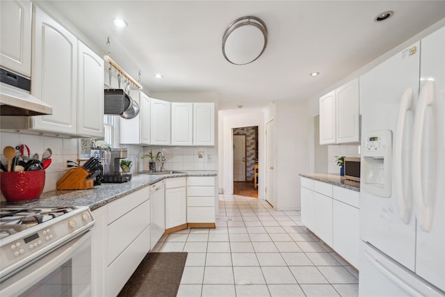 kitchen featuring tasteful backsplash, white cabinetry, white appliances, under cabinet range hood, and light tile patterned floors