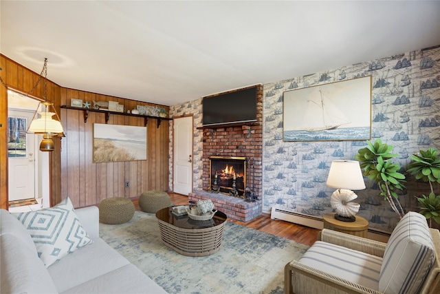 living room with a baseboard radiator, wood finished floors, wallpapered walls, wooden walls, and a fireplace