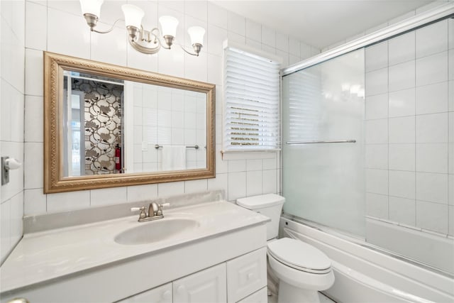 bathroom featuring vanity, tile walls, bath / shower combo with glass door, backsplash, and toilet