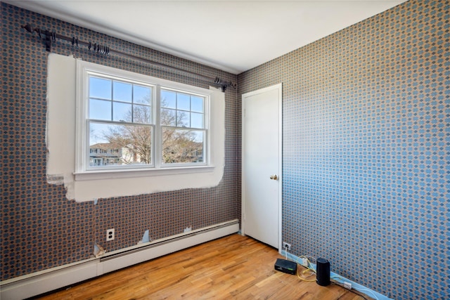 spare room with light wood-type flooring, wallpapered walls, and a baseboard radiator
