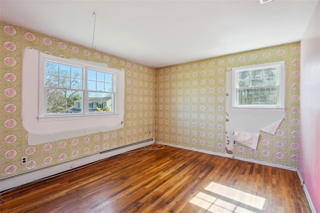 spare room featuring wallpapered walls, baseboard heating, baseboards, and hardwood / wood-style flooring