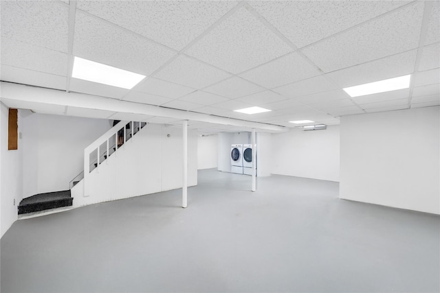 finished below grade area featuring washing machine and dryer, stairway, and a paneled ceiling