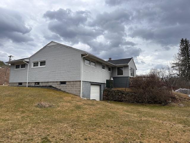 view of side of property with an attached garage and a lawn