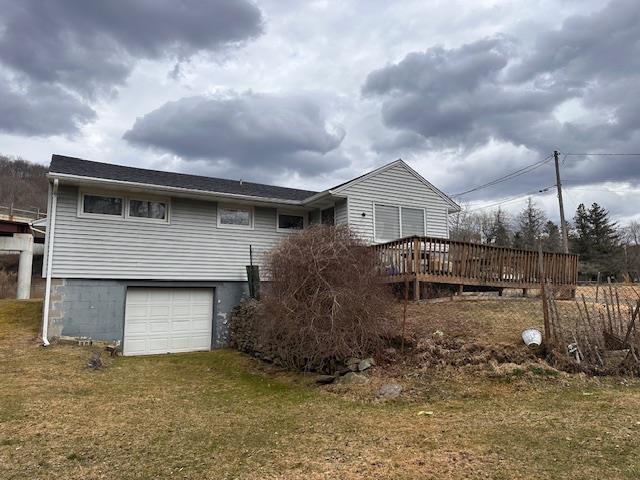 back of house with a lawn, a wooden deck, and an attached garage