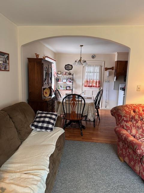 living area with arched walkways, wood finished floors, and an inviting chandelier