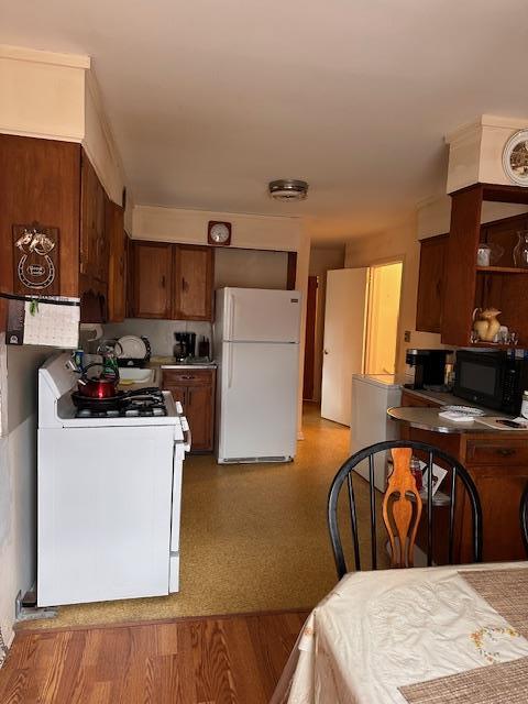 kitchen featuring brown cabinetry, light wood finished floors, and white appliances