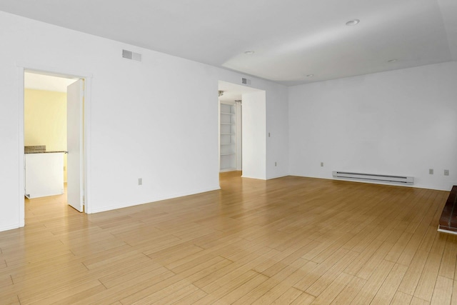 spare room with visible vents, light wood finished floors, and baseboard heating