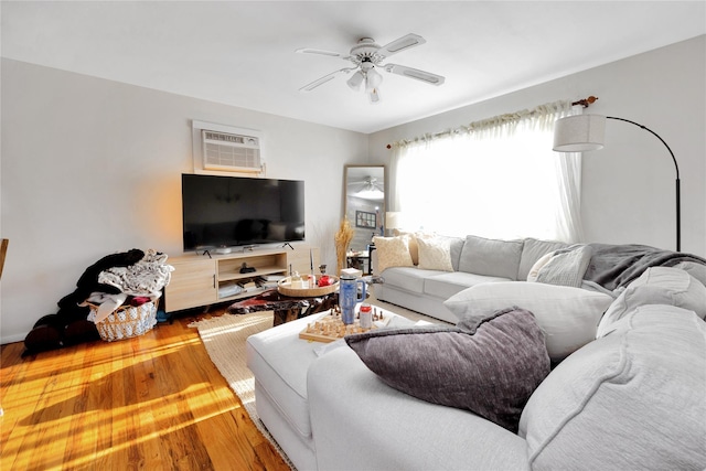 living area featuring wood finished floors, a wall unit AC, and ceiling fan