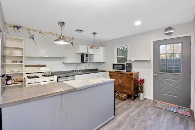 kitchen featuring a sink, stainless steel microwave, white gas stove, white cabinetry, and open shelves