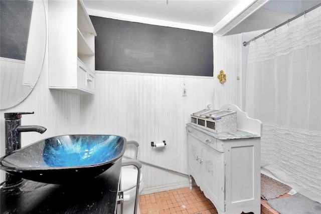 bathroom with wainscoting, wood walls, tile patterned flooring, and vanity