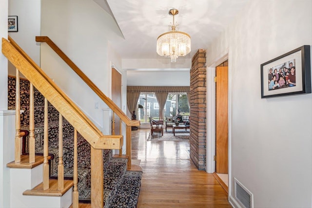 interior space with stairs, visible vents, a chandelier, and wood finished floors