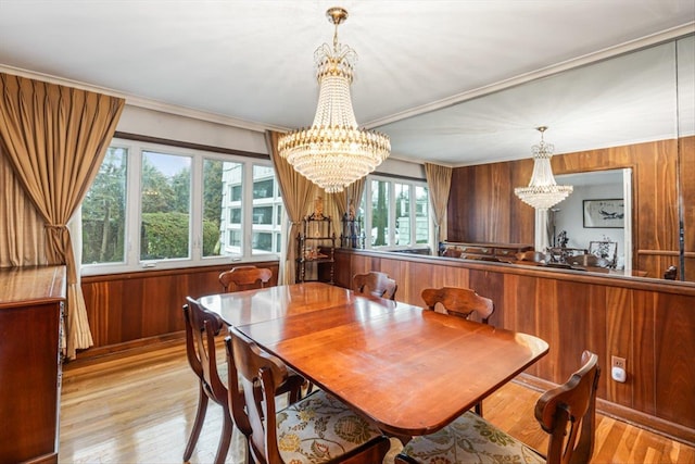 dining space with wood finished floors, a chandelier, and wooden walls