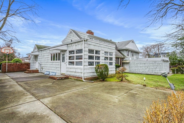 view of front of home with a front lawn, a chimney, and a patio