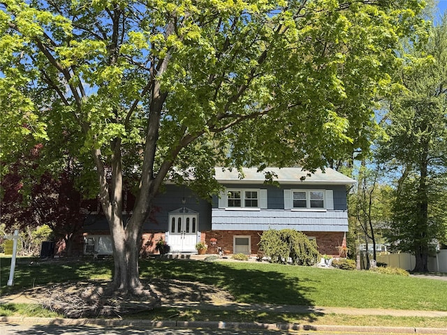view of front of house featuring brick siding, french doors, and a front yard
