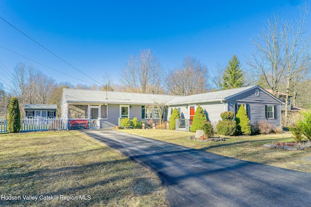ranch-style home with aphalt driveway, fence, and a front yard