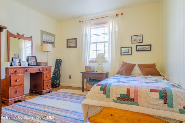 bedroom with light wood finished floors, baseboards, and ornamental molding