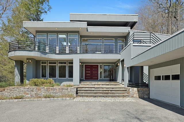 contemporary home featuring a garage, aphalt driveway, and a balcony