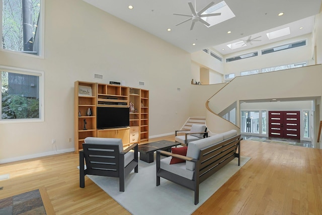 living area with a skylight, a high ceiling, wood finished floors, and a wealth of natural light