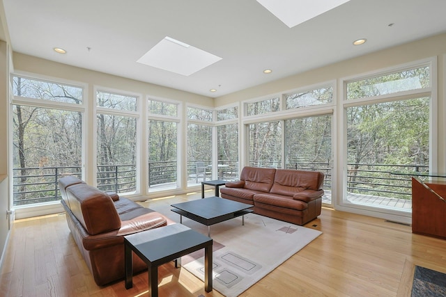 sunroom / solarium featuring a skylight, visible vents, wood finished floors, and a healthy amount of sunlight