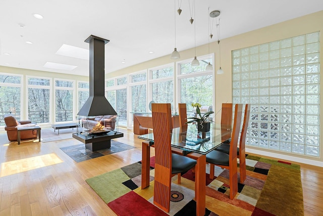 dining room with a skylight, a wood stove, recessed lighting, and wood finished floors