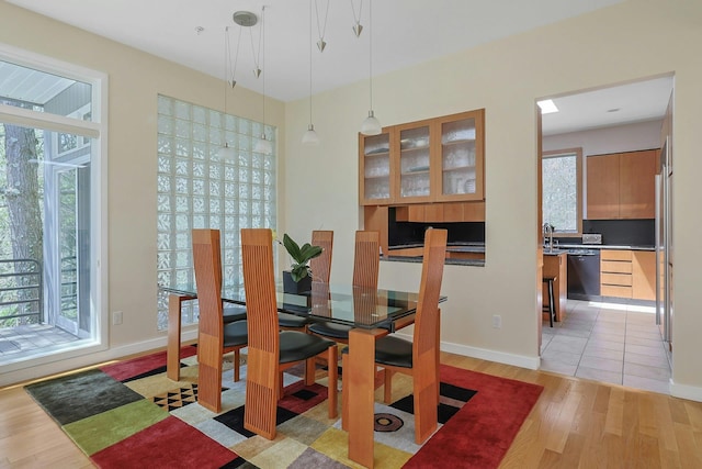 dining space with baseboards, a wealth of natural light, and light wood-style floors