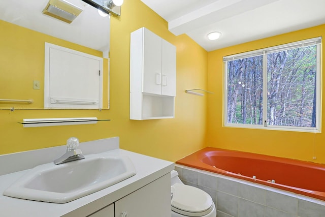 bathroom with vanity, tiled tub, and toilet